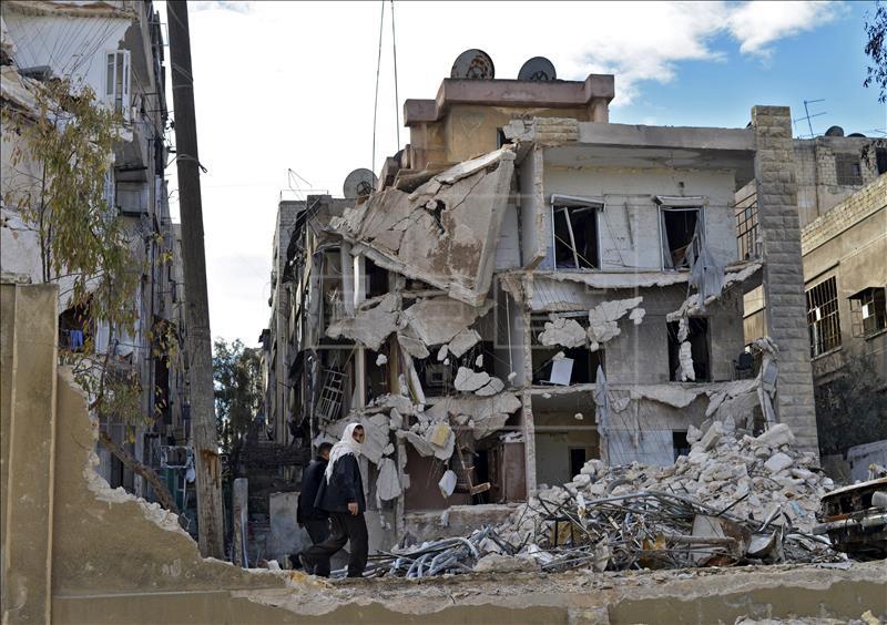 Imagen fechada el 26 de febrero de 2014, que muestra a unos civiles pasando por un edificio destruído en un ataque aéreo del régimen sirio en el barrio de Kalase en Alepo. EFE/Archivo